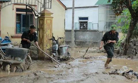 Cảnh sát cơ động giúp dân dọn bùn đất sau mưa lũ